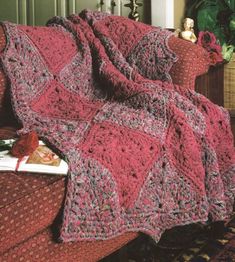 a crocheted blanket sitting on top of a couch next to a potted plant