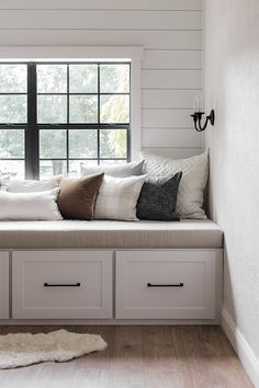 a window seat with drawers underneath it in front of a window and rug on the floor