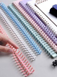 a hand is pointing at several different colored clips on a table next to each other