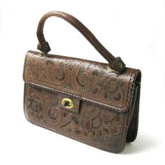 "Very nice vintage leather bag with hand-tooled designs. The bag has beautiful swirling western style design with flowers on the front, back and flap. Brass colored metal clasp. There are two interior sections divided by a zipped center section. There is also one side pocket. Measures 10.6\" x 6.5\" x 2.5\" deep. Genuine Leather, Gaitan, Made in Mexico The tooled leather sections are in wonderful shape. There are some minor scuffs from use but overall this is in very nice condition, inside and o Tooled Leather Bag, Western Purses, Leather Saddle Bags, Vintage Leather Bag, Hand Tooled Leather, Vintage Tools, Vintage Purse, Silver Shoes, Tooled Leather