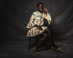 a woman sitting in a chair with her legs crossed and wearing high heels, smiling at the camera