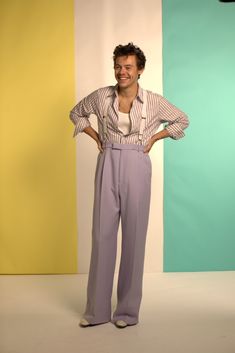 a man standing with his hands on his hips in front of a multi - colored backdrop