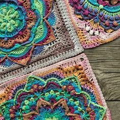 three crocheted squares with different designs on them sitting on a wooden table top