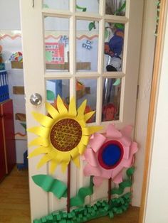 a door decorated with paper flowers in front of a child's playroom window