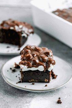 two pieces of chocolate cake sitting on top of white plates with marshmallows