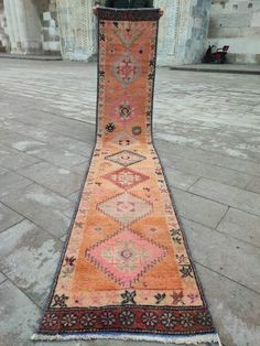 an old rug is laying on the ground in front of a building with columns and pillars