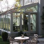 two chairs and a table in front of a house with large glass windows on the side