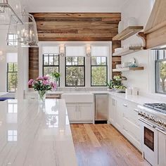 a large kitchen with white cabinets and wood paneling on the walls, along with marble counter tops