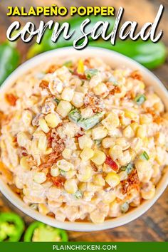 a white bowl filled with corn on top of a wooden table next to green peppers