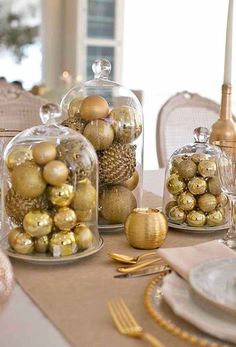 the table is set with gold and silver ornaments in glass domes on top of each other