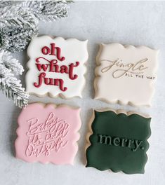 four decorated cookies sitting on top of a table next to a christmas tree and snow