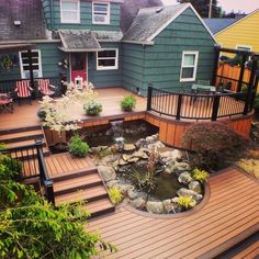 a wooden deck with water feature and steps leading to the front door, next to a small pond