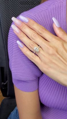 a woman wearing a purple sweater and holding her hand on her shoulder with a diamond ring