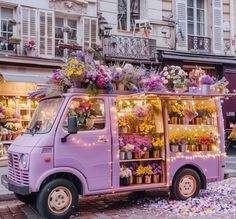 a purple van with flowers on the back parked in front of a building and surrounded by confetti