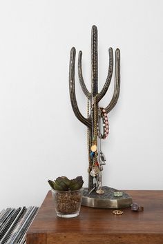 a metal cactus on top of a wooden table next to a record player and a potted plant