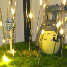 some lights that are in the grass near a building and a cat statue with eyes on it