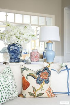 blue and white vases are sitting on the couch in this living room with floral pillows