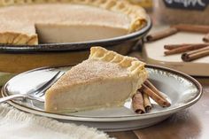 a slice of pie on a plate with cinnamon sticks next to it and two other pies in the background