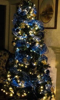 a blue christmas tree decorated with lights and bows