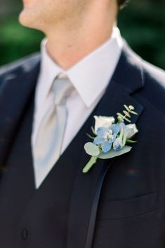 a man in a suit and tie wearing a boutonniere with flowers on it