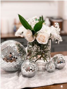 a vase filled with white flowers sitting on top of a table next to disco balls