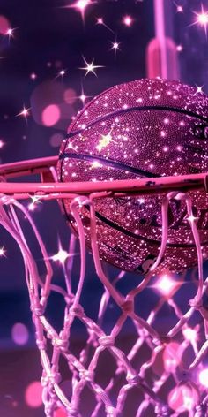 a close up of a basketball going through the net with stars in the sky behind it