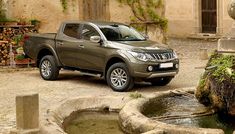 a silver truck parked in front of a building next to a small fountain with moss growing on it