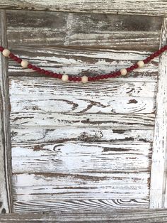 a red string with white beads is hanging on a wooden door, next to a small beaded necklace