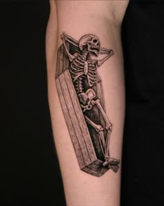 a tattoo on the arm of a person with a cross and a skeleton in it