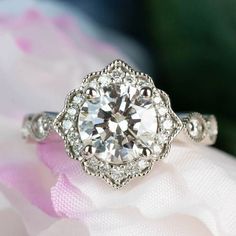 a close up view of a diamond ring on top of a pink flowered cloth