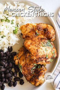 mexican style chicken thighs with black beans and rice on a white plate next to a striped towel