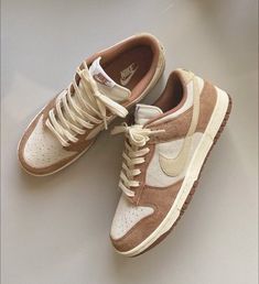 a pair of brown and white sneakers on top of a gray table next to an apple