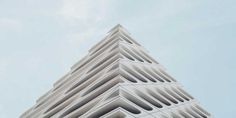 a very tall white building with many windows on it's side and the sky in the background