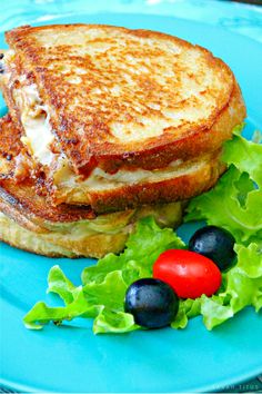 a grilled cheese sandwich on a blue plate with lettuce and tomatoes