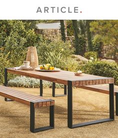 a wooden table with two benches next to it and some fruit on the plate near by