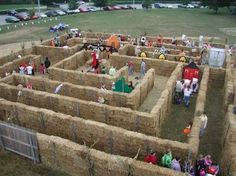 people are gathered in hay bales to look at an outdoor play area that looks like it has been built into the ground