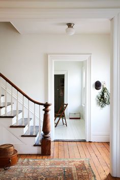 an entry way with stairs and rugs on the floor