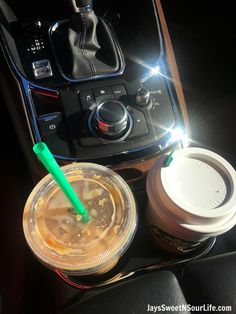 there are two drinks in the cup on the car dash board and one is empty