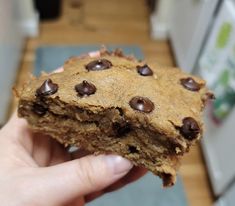 someone holding up a cookie with chocolate chips on it