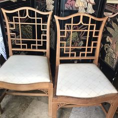 two wooden chairs with white upholstered cushions