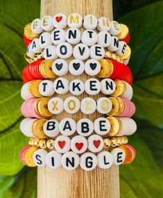 a stack of bracelets with words written in different colors and shapes on top of each other