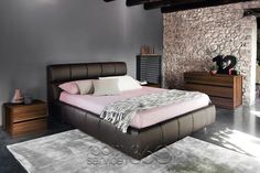 a bedroom with stone walls and flooring has a large bed in the center, along with two nightstands on either side