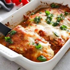 a casserole dish with meat, cheese and spinach on the side is being held by a spatula