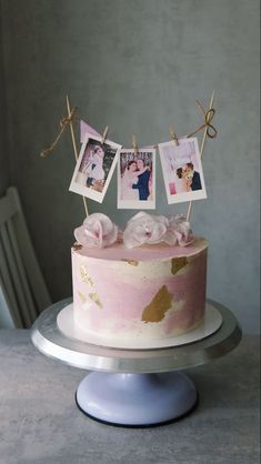 a pink cake with photos hanging from it