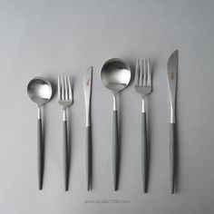 five spoons, two forks and one knife are arranged in a row on a gray surface