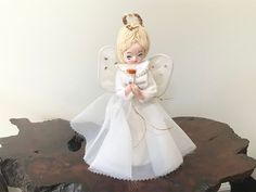 an angel figurine sitting on top of a piece of wood