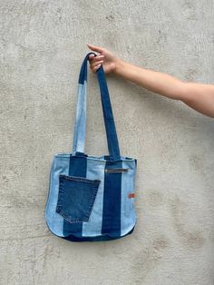 a person holding onto a blue and white striped tote bag with one hand in the pocket