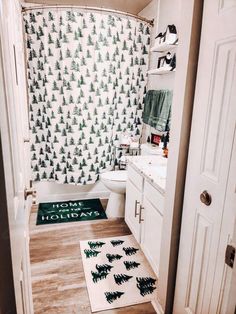 a bathroom with christmas trees on the shower curtain and rug in front of the tub