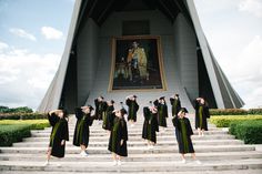 a group of people standing on steps in front of a building with a painting behind them