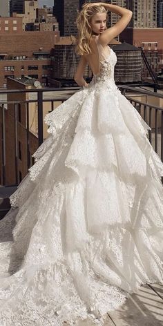 a woman in a white wedding dress standing on a balcony with her hand on her head